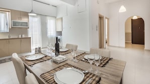 Et moderne spiseområde med et træbord dækket til fire personer, omgivet af beige stole.