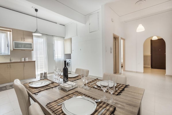 A modern dining area with a wooden table set for four, surrounded by beige chairs. - Mirsini's Apartment in Chania center (Chania)