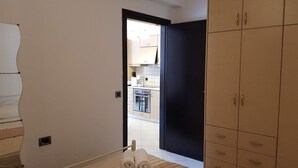 A bedroom with a bed, a wardrobe, and a bathroom visible through an open door. - Ilia's Apt in Chania (Chania)