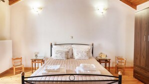A bedroom with a bed, two bedside tables, a wardrobe, and a wooden ceiling. - Traditional Stone House Rafael (Tzitzifes)