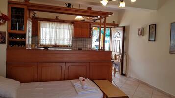 Une chambre à coucher avec une tête de lit en bois, un lit recouvert de draps blancs, un banc et une petite table.