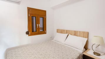 Une chambre à coucher avec un lit, une tête de lit en bois, une table de chevet avec une lampe et une porte en bois dotée de panneaux de verre.