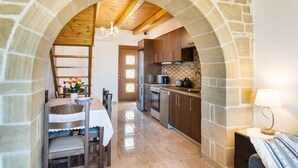 Une cuisine dotée d’arcs en pierre, de poutres apparentes en bois au plafond et d’appareils électroménagers modernes.
