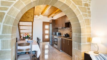 Une cuisine dotée d’arcs en pierre, de poutres apparentes en bois au plafond et d’appareils électroménagers modernes.