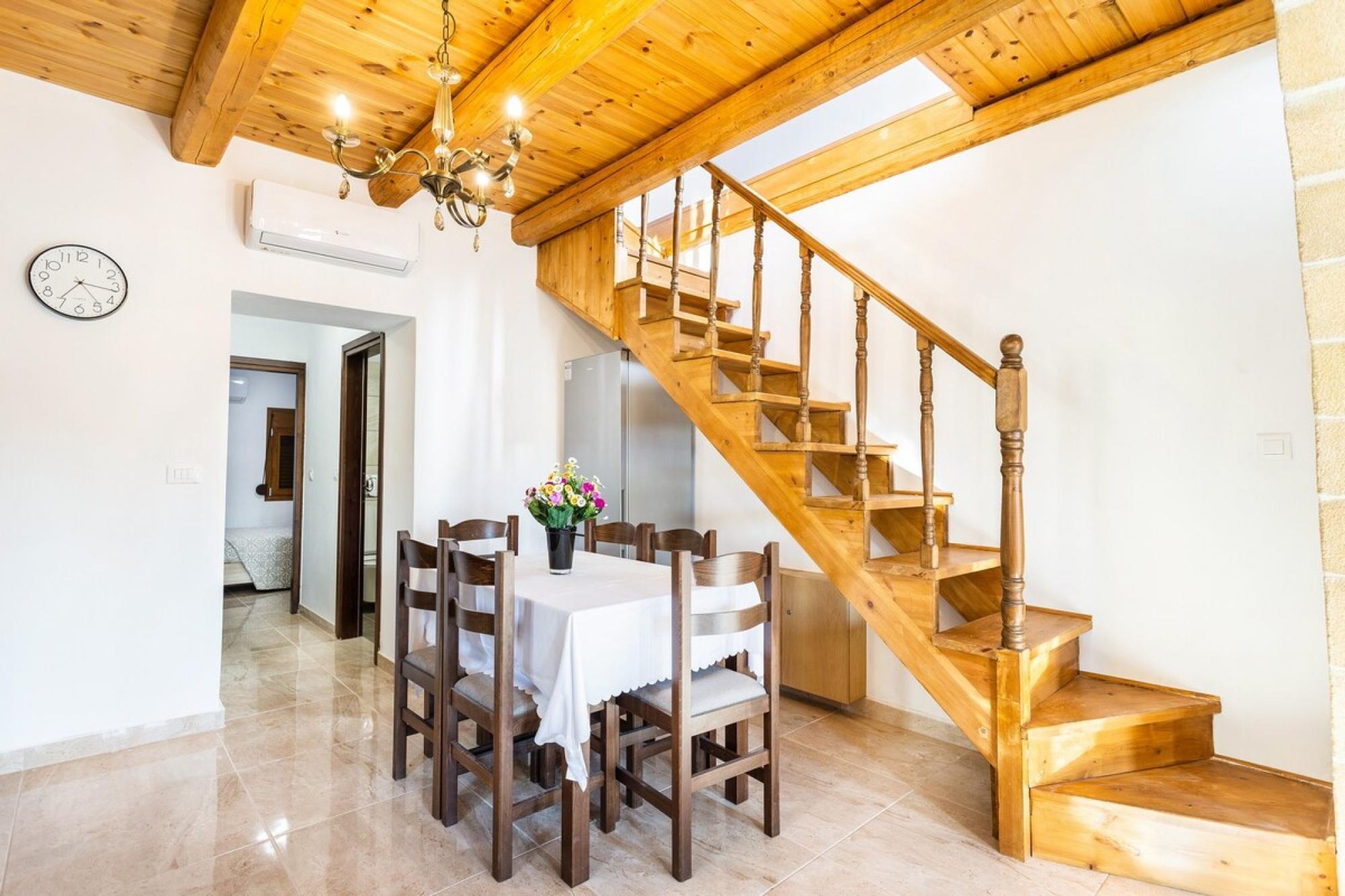 Un espace repas agrémenté d’un escalier en bois et d’un lustre.