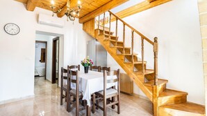 Un espace repas agrémenté d’un escalier en bois et d’un lustre.