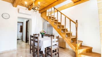 Un espace repas agrémenté d’un escalier en bois et d’un lustre.