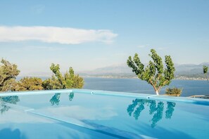 Una piscina a sfioro cristallina con vista sul mare e sulle montagne.