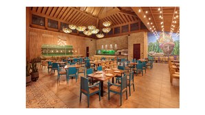 Un restaurant spacieux avec de hauts plafonds en bois, des luminaires décoratifs en forme de fleurs suspendus et une grande fresque murale au fond de la salle.