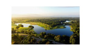 Un parcours de golf avec un grand lac, entouré d’arbres et de vastes étendues de terrain découvert.