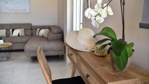 Una sala de estar con un sofá, una mesita de madera con un sombrero y una planta, y una silla.
