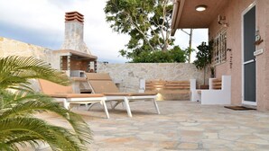 Un patio de piedra con sillones de descanso, una chimenea de piedra y vistas del paisaje circundante.