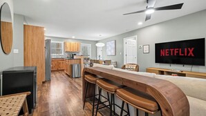 Eine moderne Küche mit Holzausstattung, einem Einbaukühlschrank und einer Bar mit Hockern.