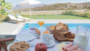A breakfast setup with a view of a pool and mountains. - Villa Erato – Agios  Onoufrios (Kounoupidiana)