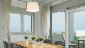 Een moderne eetruimte met een houten tafel, zes grijze bekleden stoelen en drie witte potten met groene planten.