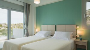 Een hotelkamer met twee bedden, een groot raam en uitzicht op het landschap.