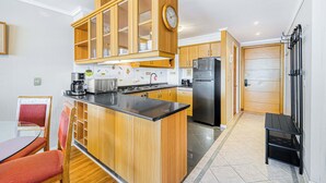 A modern kitchen with wooden cabinets, a central island, and a built-in clock. - Rincón Almar 2D, Wifi & Estacionamiento (Viña del Mar)