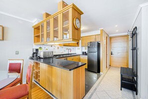 A modern kitchen with wooden cabinets, a central island, and a built-in clock.