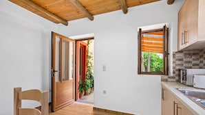 A modern kitchen with wooden cabinets, a built-in oven, and a window with blinds. - Maria's House with View in Kambos (Kampos)