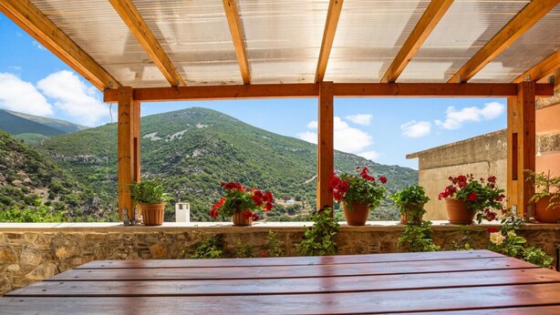 A wooden table under a pergola with a mountain view. - Maria's House with View in Kambos (Kampos)