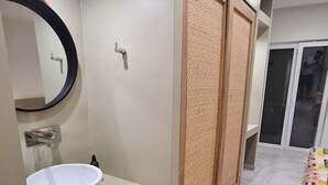 Une salle de bain moderne avec un miroir rond, un lavabo blanc et une cloison en bois.