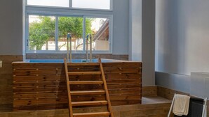 Ein Badezimmer mit einer Holzbank, einer Holzeiter und einem Fenster mit Blick auf Bäume und ein Gebäude.