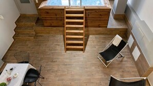 Ein modernes Badezimmer mit Holzboden, einer Badewanne, einer Holzleiter und zwei schwarzen Lounge-Sesseln.