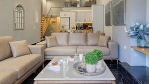 Ein modernes Wohnzimmer mit einer Couch, einem Couchtisch und einem Essbereich, der zu einer oberen Ebene führt.