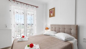 Een hotelkamer met een bed, een raam met gordijnen, een bedlamp en een ingelijst schilderij aan de muur.