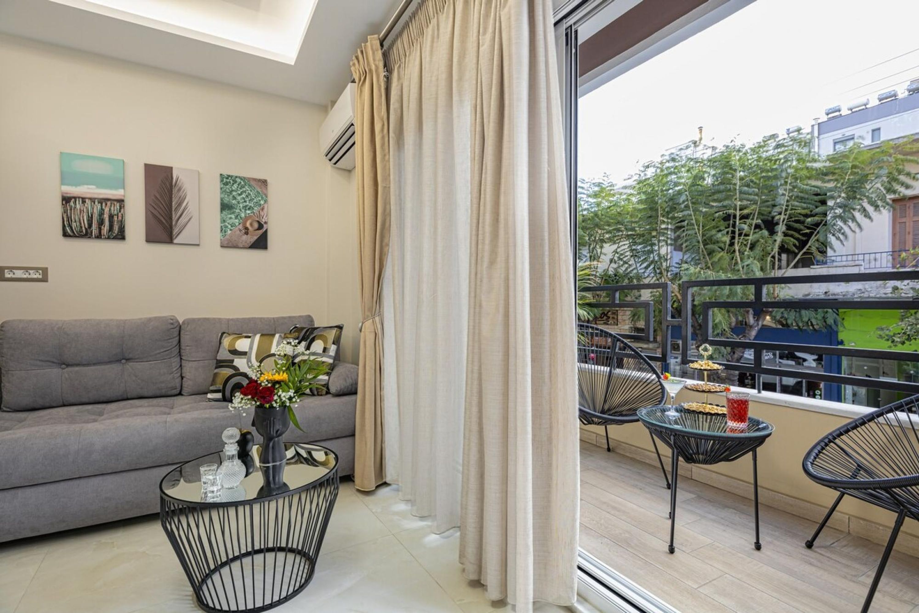 Un soggiorno moderno con un divano grigio, un tavolino in vetro e un balcone con posti a sedere esterni.