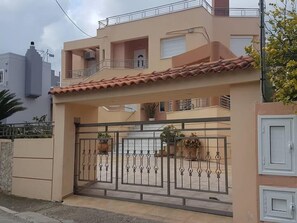 A modern two-story house with a tiled roof, a gated entrance, and a balcony. - Sofie's Garden View Apartment (Daratsos)