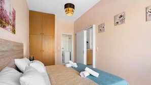A hotel room with a bed, a wardrobe, a bathroom, and artwork on the walls. - Sun & Beach Apartments in Chania 11 (Chania)