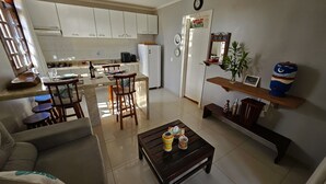A spacious living area with a kitchen, dining table, and comfortable seating. - Chalé De Canoa (Aracati)