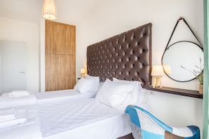 Ein Hotelzimmer mit einem großen Bett, einem Holzschrank, einem runden Spiegel und einem kleinen Tisch mit einer Lampe.