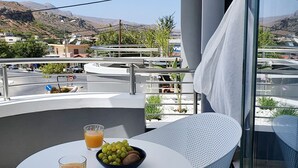 Een balkon met een tafel, twee sinaasappelsappen en een fruitschaal.