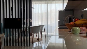 Een moderne keuken met een groot raam, een eethoek met stoelen en een keukentrap met fruit.