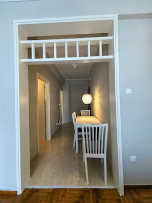 Ein Zimmer mit Esstisch und Stühlen, einer Deckenleuchte und einer Tür zu einem anderen Raum.