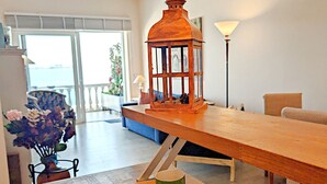 Un espace repas avec une table en bois, une lanterne et une vue sur l’extérieur.