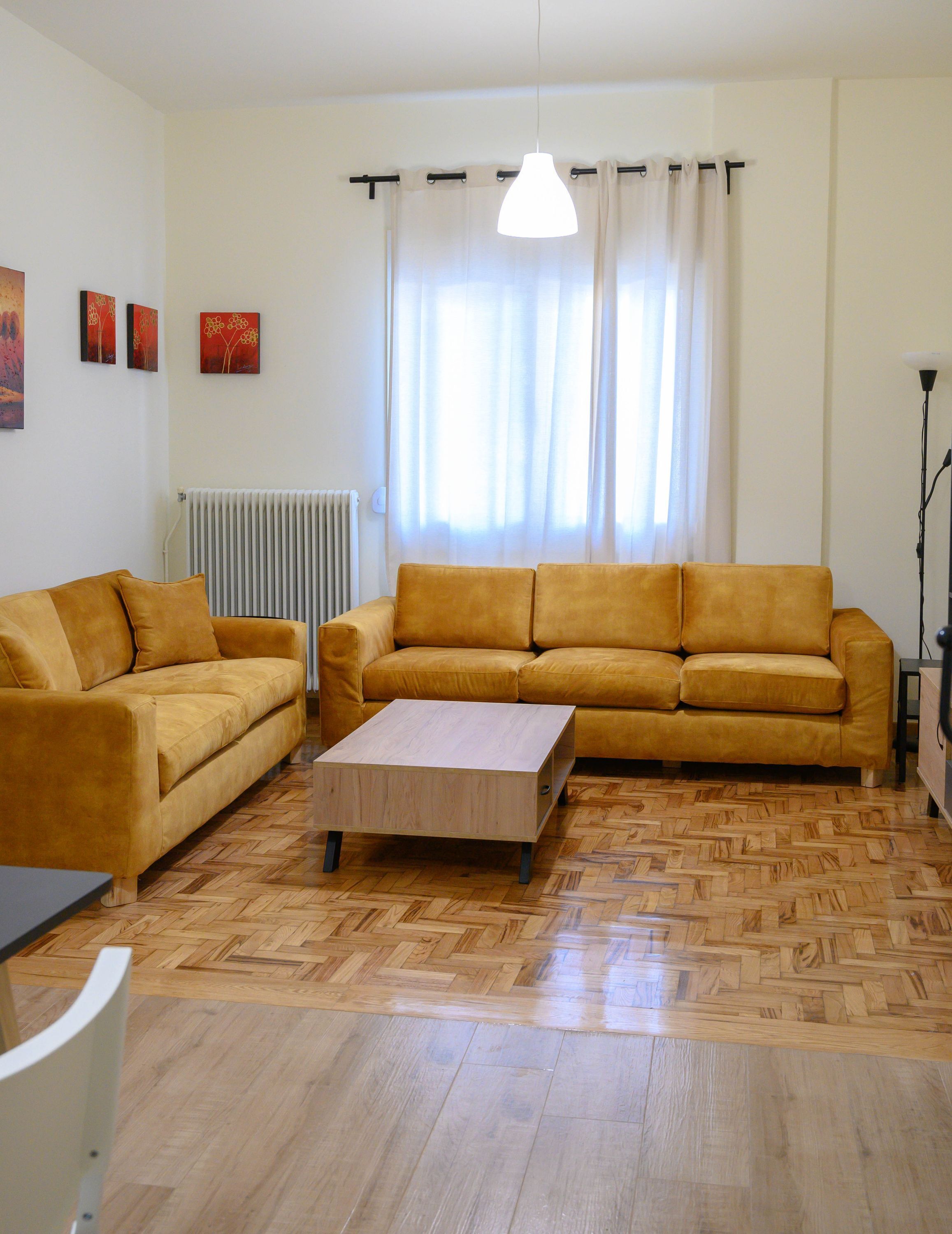 Un salon avec deux canapés, une table basse, un radiateur et une lampe sur pied.