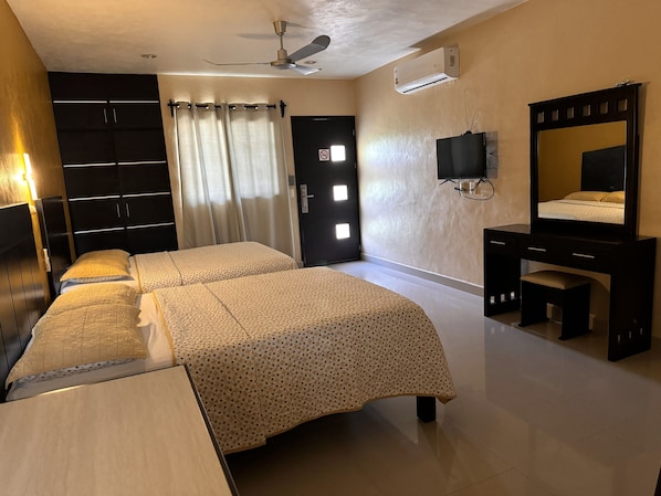A hotel room with a bed, a desk, a chair, a TV, a mirror, a ceiling fan, and an air conditioning unit. - Hotel Avila (Valladolid)