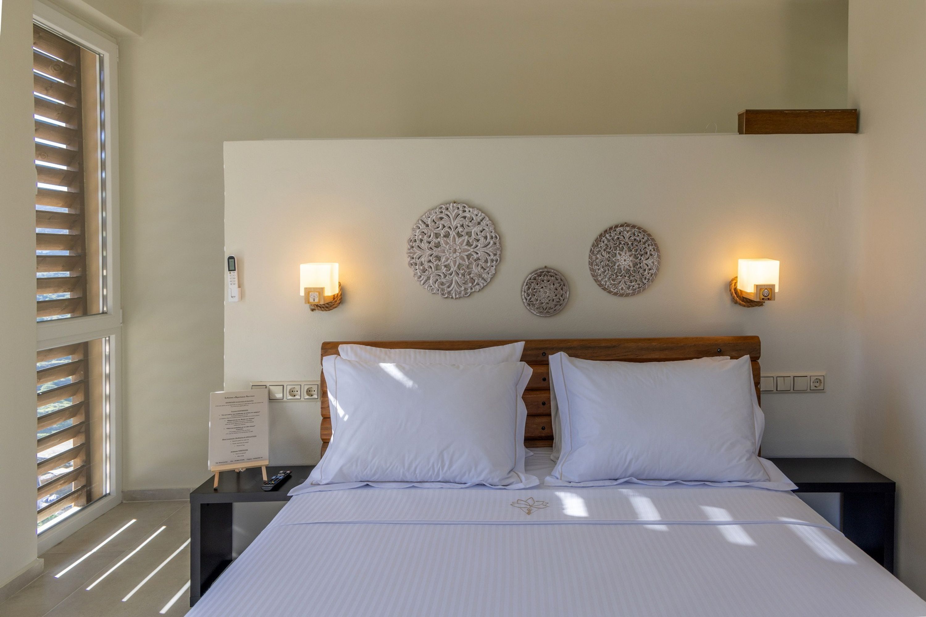 A neatly arranged hotel room with a bed, bedside tables, wall-mounted lights, and decorative wall art.