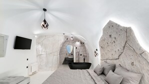 Een moderne slaapkamer met een groot bed, een ingebouwd bad en een boog van natuursteen.