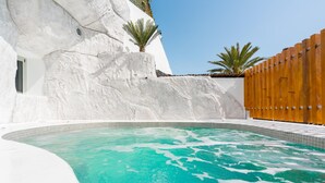 Een zwembad met helder turquoise water, omringd door witte muren en een houten omheining.