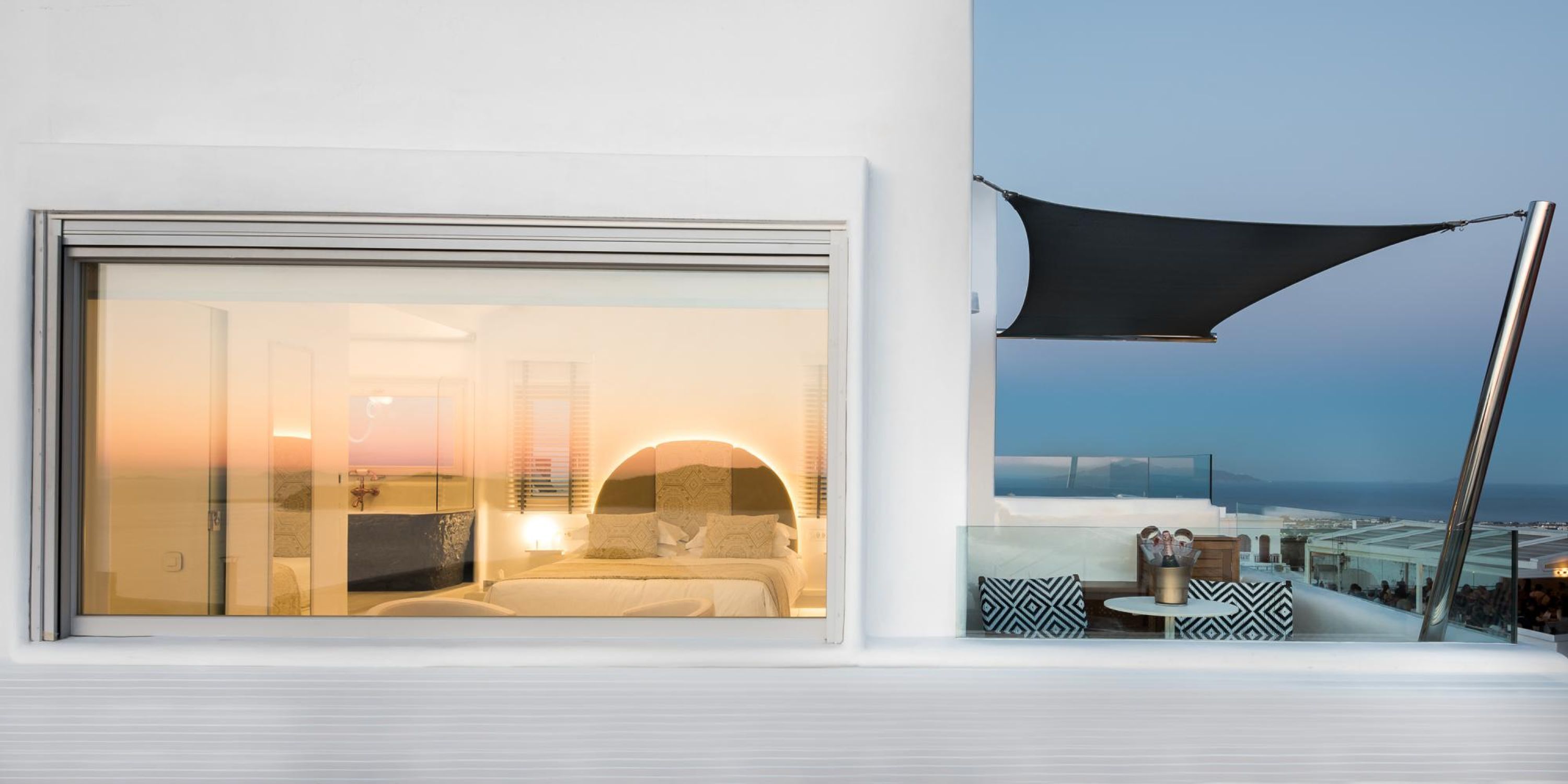 Une chambre d’hôtel moderne dotée d’une grande fenêtre, d’un balcon avec vue et d’un auvent.