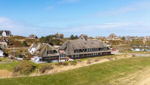 En kustby med traditionella hus som har stråtak, en grönskande förgrund och en klar himmel.