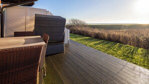 A covered outdoor seating area with a view of a grassy field and a clear sky. - Apartment Watt directly on the mudflats in Rantum on Sylt (Sylt)