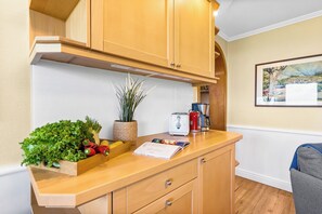 Una cocina con armarios de madera, una encimera con productos frescos, una tetera y una cafetera.