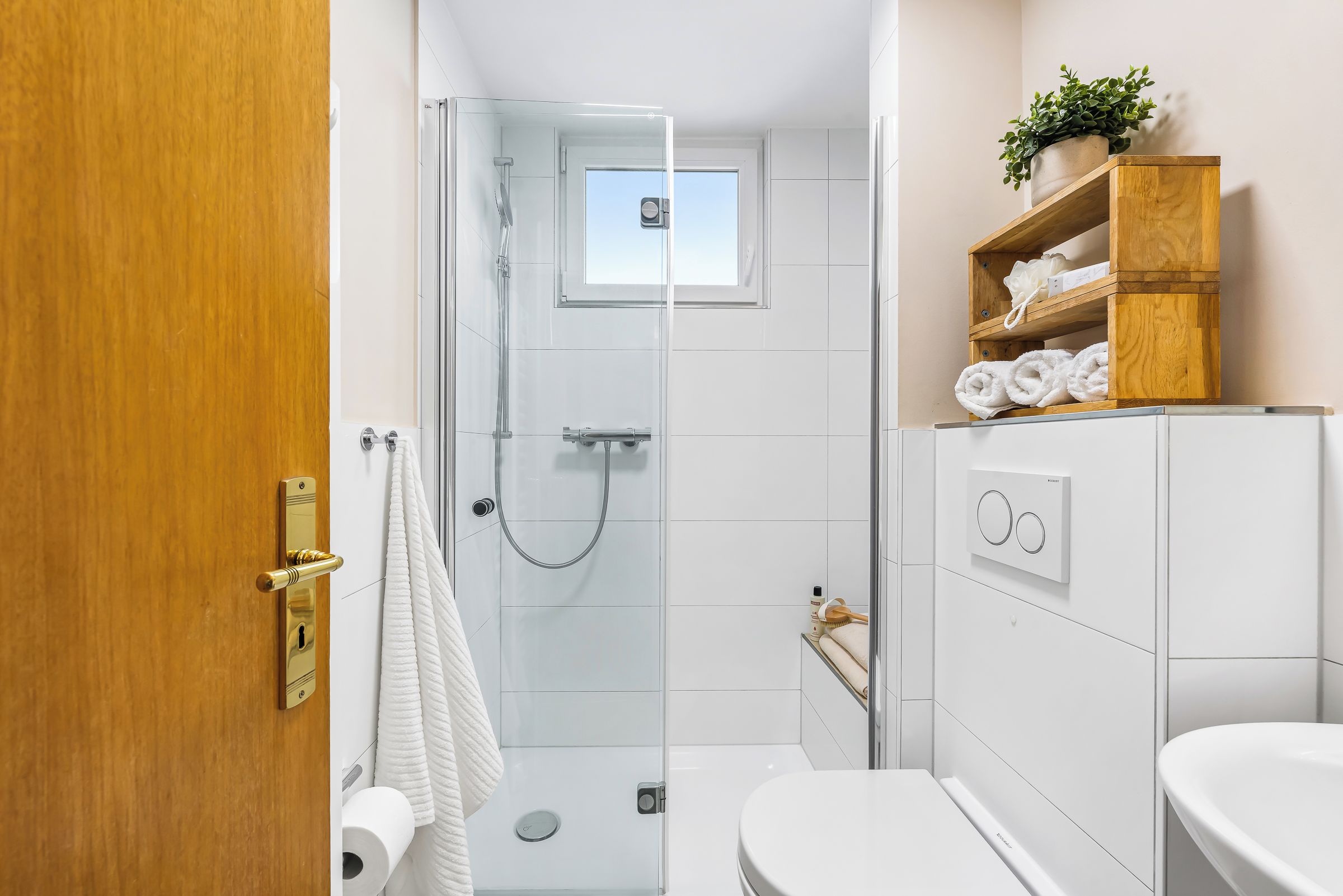 A modern bathroom with a glass shower enclosure, a toilet, and a sink.
