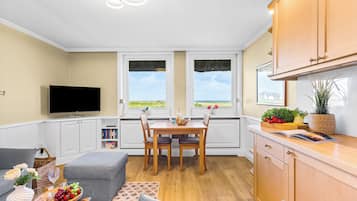 Un espacio habitable compacto con comedor, kitchenette y televisor.