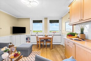 Un espacio habitable compacto con comedor, kitchenette y televisor.